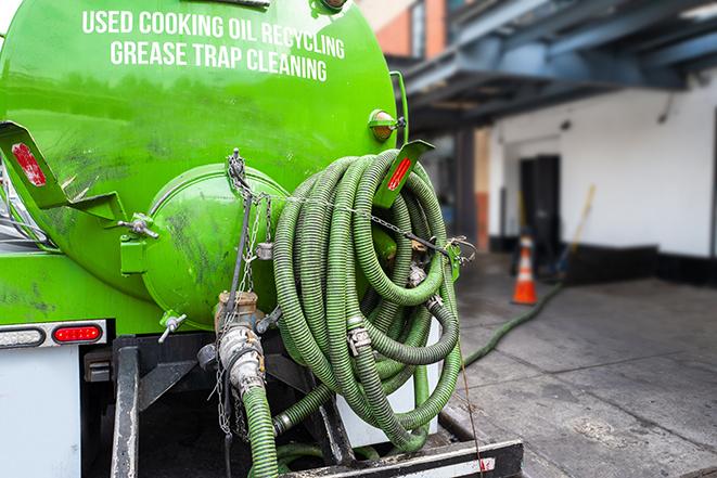 a technician pumping a grease trap in a commercial building in Carrollton